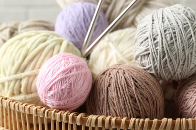 Photo of Balls of colorful yarn in wicker basket, closeup