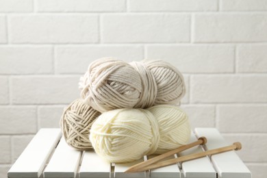 Photo of Skeins of yarn and knitting needles on white wooden table