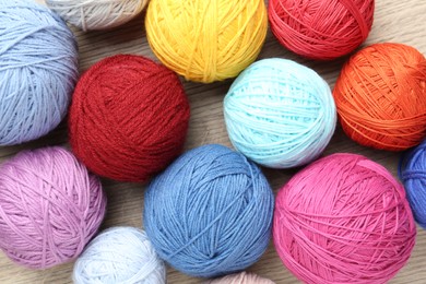 Balls of colorful yarn on wooden table, flat lay