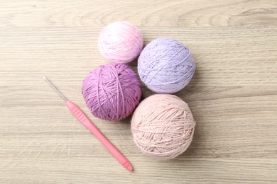 Photo of Balls of colorful yarn and crochet hook on wooden table, flat lay