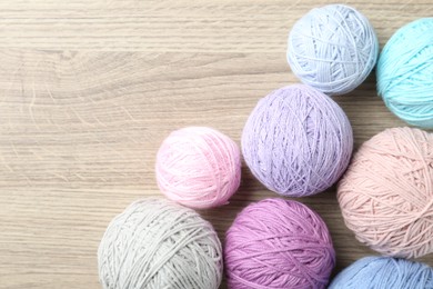 Photo of Balls of colorful yarn on wooden table, flat lay. Space for text