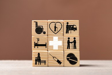 Image of Stacked wooden cubes with healthcare icons on table against pale brown background