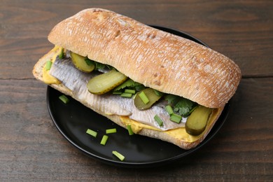 Tasty sandwich with herring, pickles, green onions and parsley on wooden table, closeup