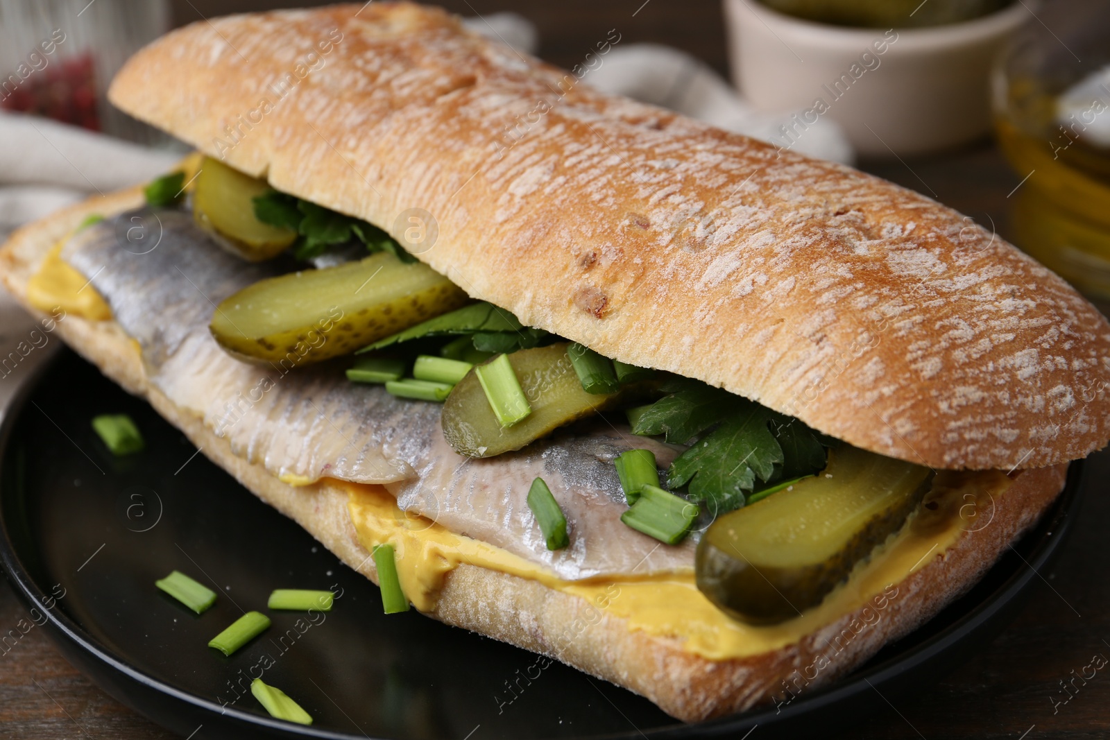 Photo of Tasty sandwich with herring, pickles, green onions and parsley on table, closeup