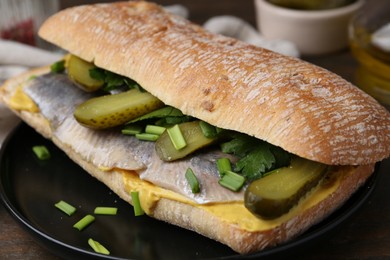 Tasty sandwich with herring, pickles, green onions and parsley on table, closeup