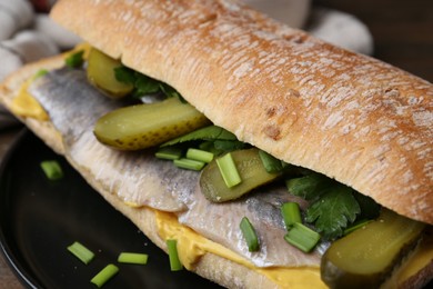 Photo of Tasty sandwich with herring, pickles, green onions and parsley on table, closeup