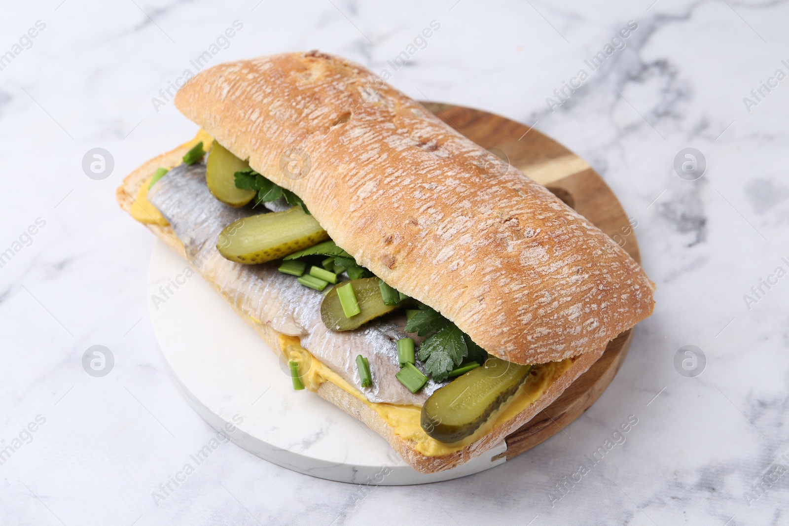 Photo of Tasty sandwich with herring, pickles, green onions and parsley on white marble table, closeup