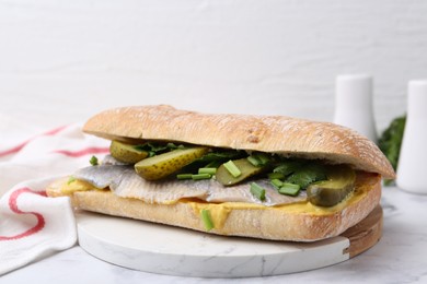 Tasty sandwich with herring, pickles, green onions and parsley on white marble table, closeup