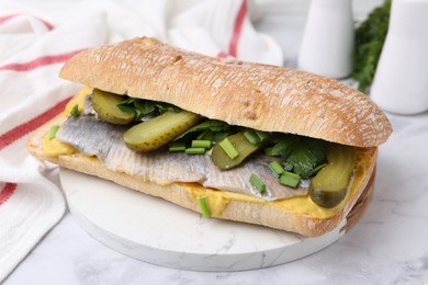 Photo of Tasty sandwich with herring, pickles, green onions and parsley on white marble table, closeup