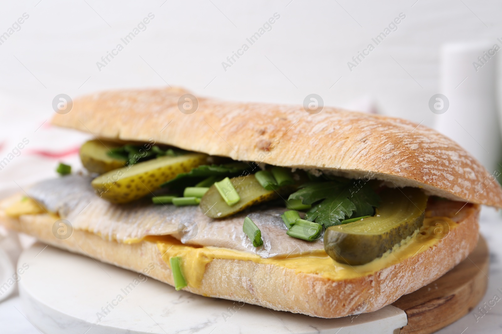 Photo of Tasty sandwich with herring, pickles, green onions and parsley on table, closeup