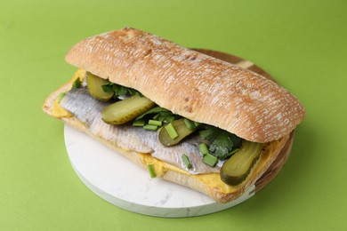 Photo of Tasty sandwich with herring, pickles, green onions and parsley on color background, closeup