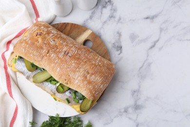 Tasty sandwich with herring, pickles, green onions and dill on white marble table, flat lay. Space for text