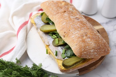 Tasty sandwich with herring, pickles, green onions and parsley on white marble table, closeup