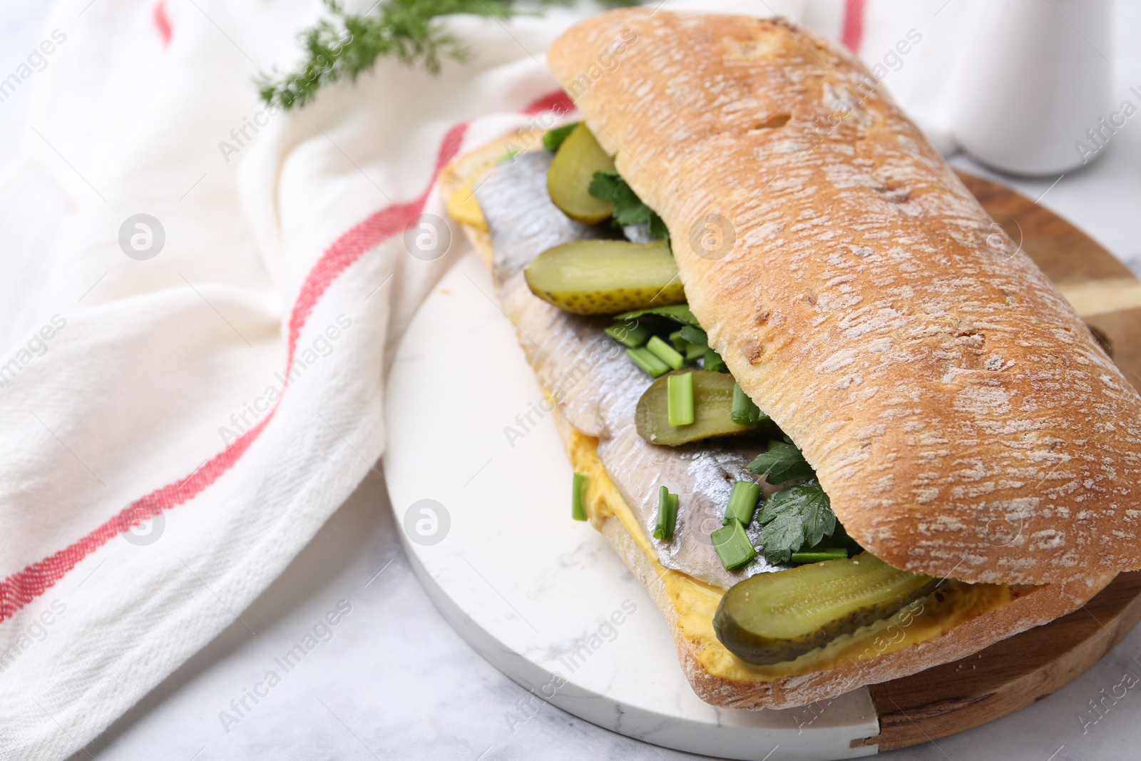 Photo of Tasty sandwich with herring, pickles, green onions and parsley on white marble table, closeup