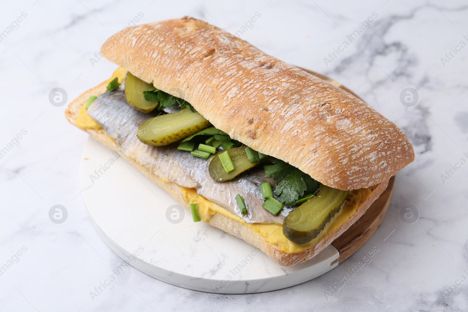 Photo of Tasty sandwich with herring, pickles, green onions and parsley on white marble table, closeup