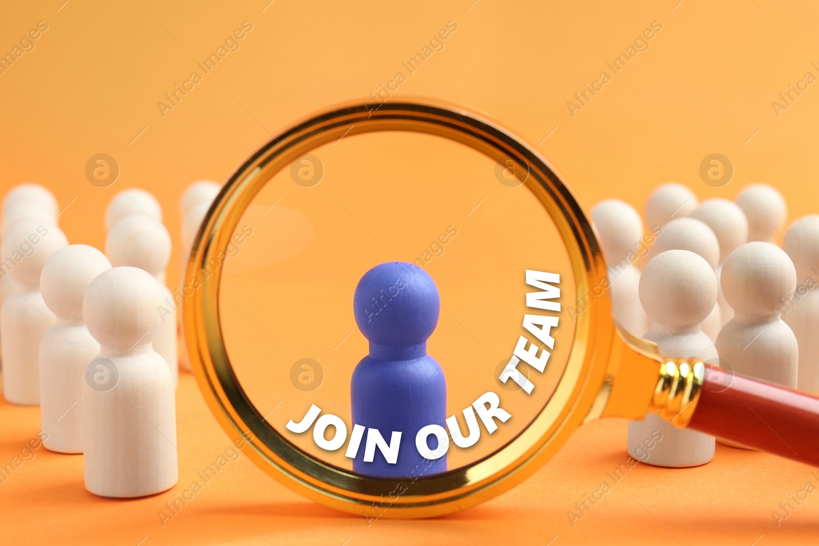 Image of Join Our Team announcement. Blue figure among wooden ones on orange background, view through magnifying glass. Human resource