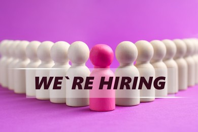 Image of We Are HIring announcement. Pink figure among white ones on violet background. Human resource