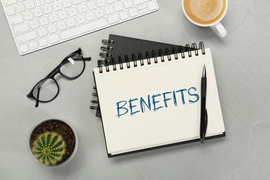 Image of Benefits word in notebook, pen, coffee, eyeglasses and computer keyboard on grey table, top view