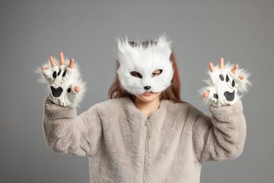 Photo of Quadrobics. Girl wearing cat mask and gloves on grey background