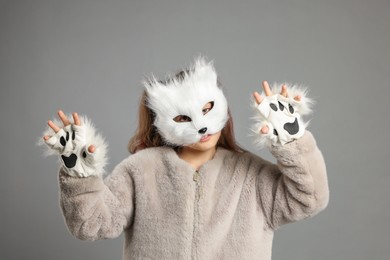 Photo of Quadrobics. Girl wearing cat mask and gloves on grey background