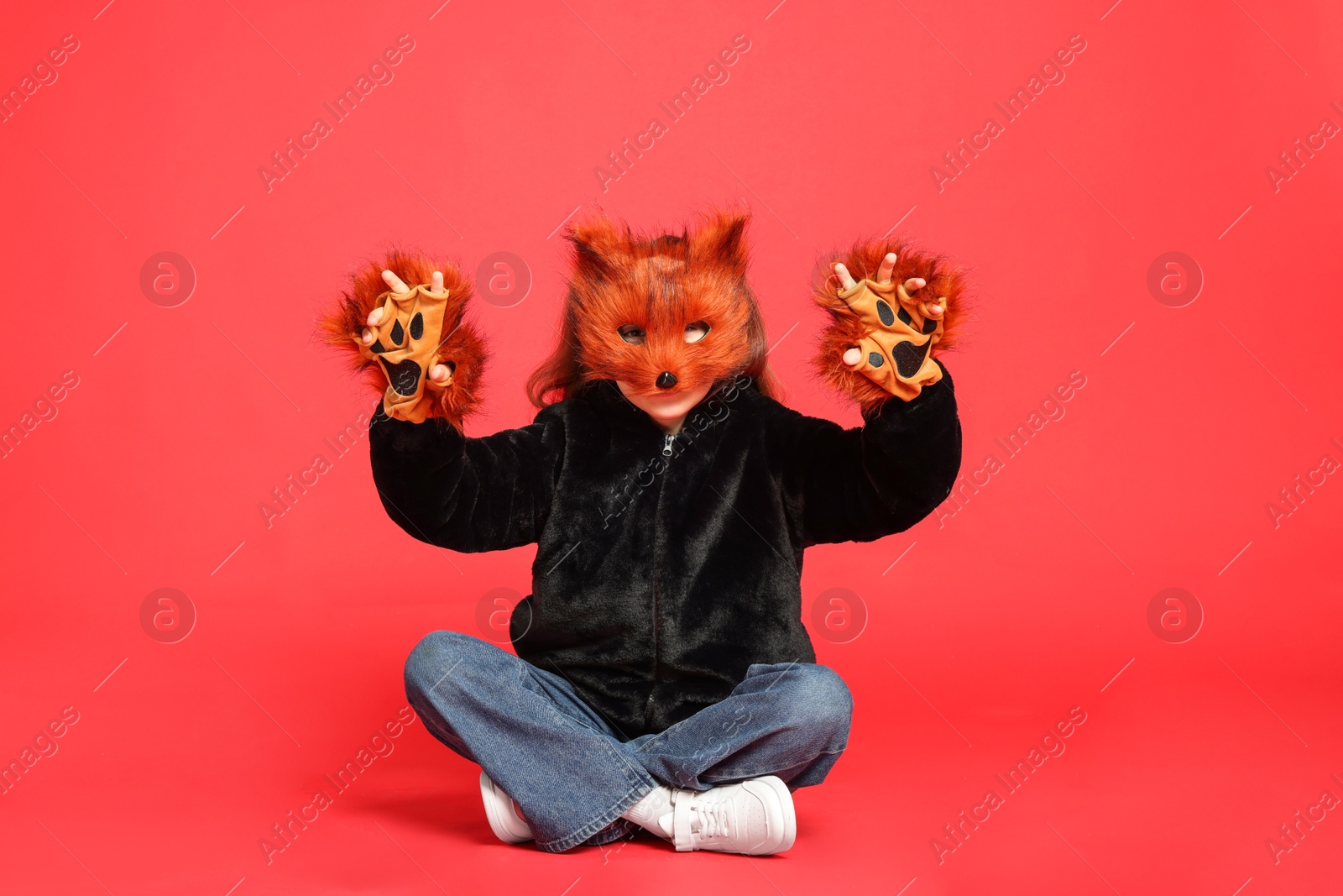 Photo of Quadrobics. Girl wearing fox mask and gloves on red background