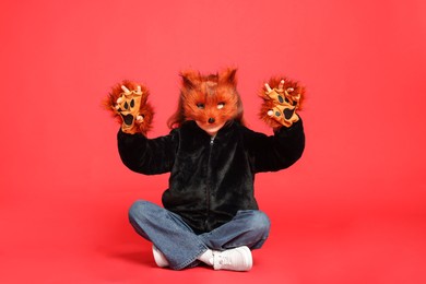 Quadrobics. Girl wearing fox mask and gloves on red background