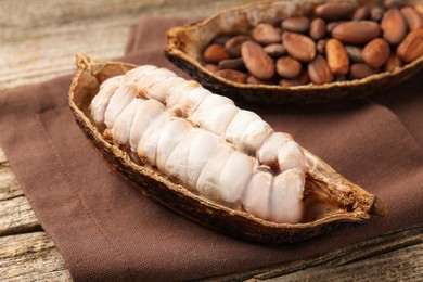 Photo of Cocoa pods with beans on wooden table, closeup