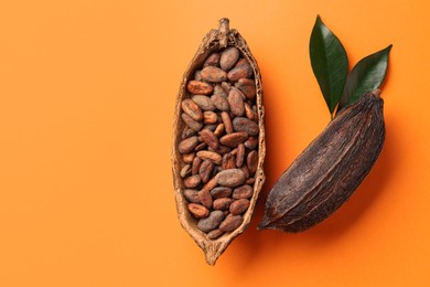 Photo of Cocoa pods with beans on orange background, top view. Space for text