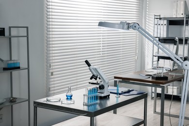 Photo of Chemical glassware and microscope on table in laboratory. Space for text