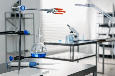 Photo of Flask with blue liquid on retort stand in laboratory. Space for text