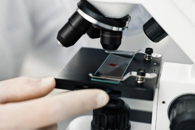 Photo of Scientist working with microscope in laboratory, closeup