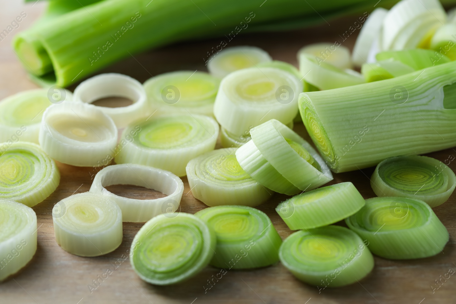 Photo of Fresh chopped leeks on wooden board, closeup