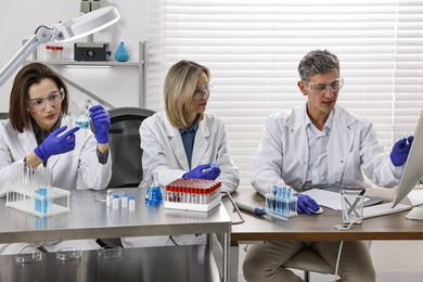 Scientists working with computer and samples at table in laboratory