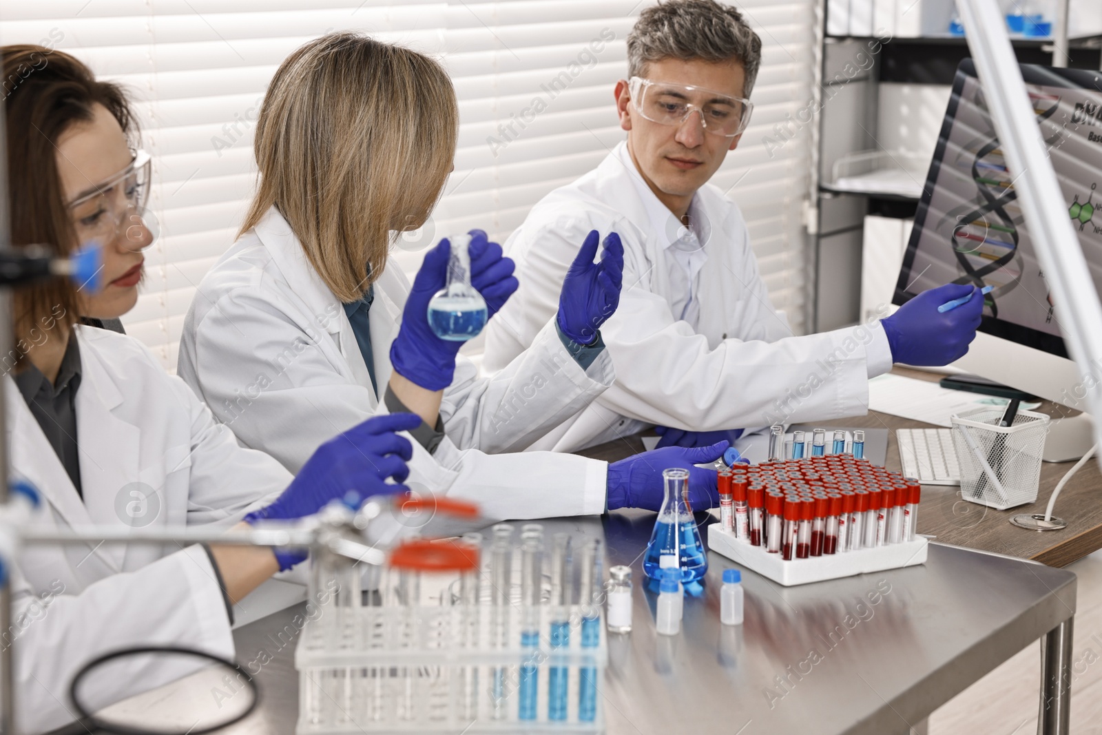 Photo of Scientists working with computer and samples at table in laboratory