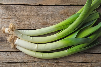 Photo of Whole fresh leeks on wooden table, top view