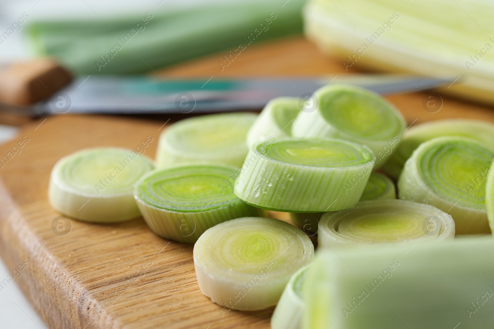 Photo of Chopped leeks, knife and board on table, closeup