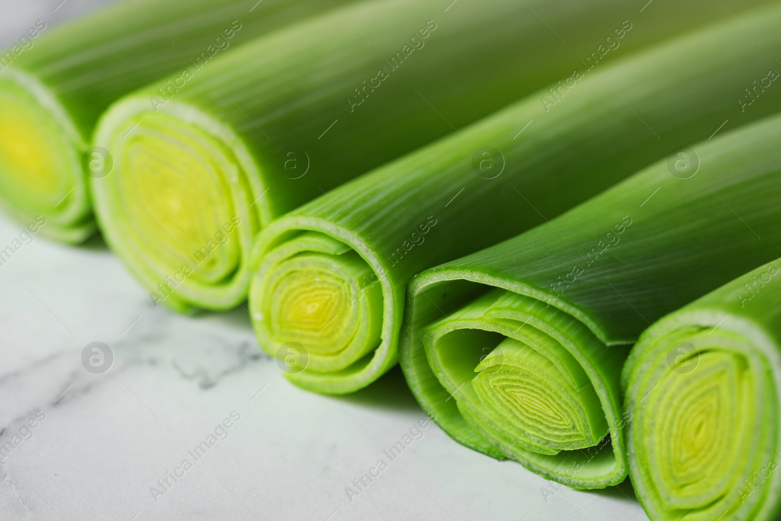 Photo of Whole fresh leeks on white marble table, closeup