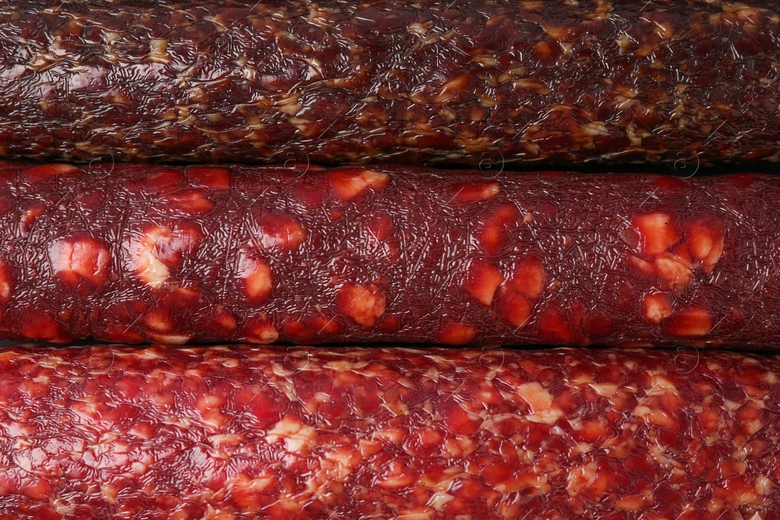 Photo of Different tasty smoked sausages as background, top view