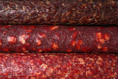 Photo of Different tasty smoked sausages as background, top view