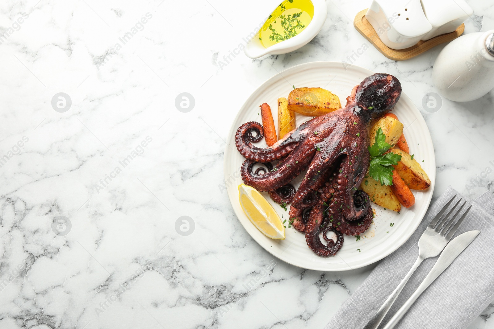 Photo of Roasted octopus with vegetables served on white marble table, flat lay. Space for text