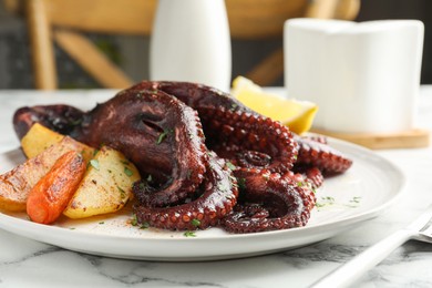 Roasted octopus with vegetables on white marble table, closeup