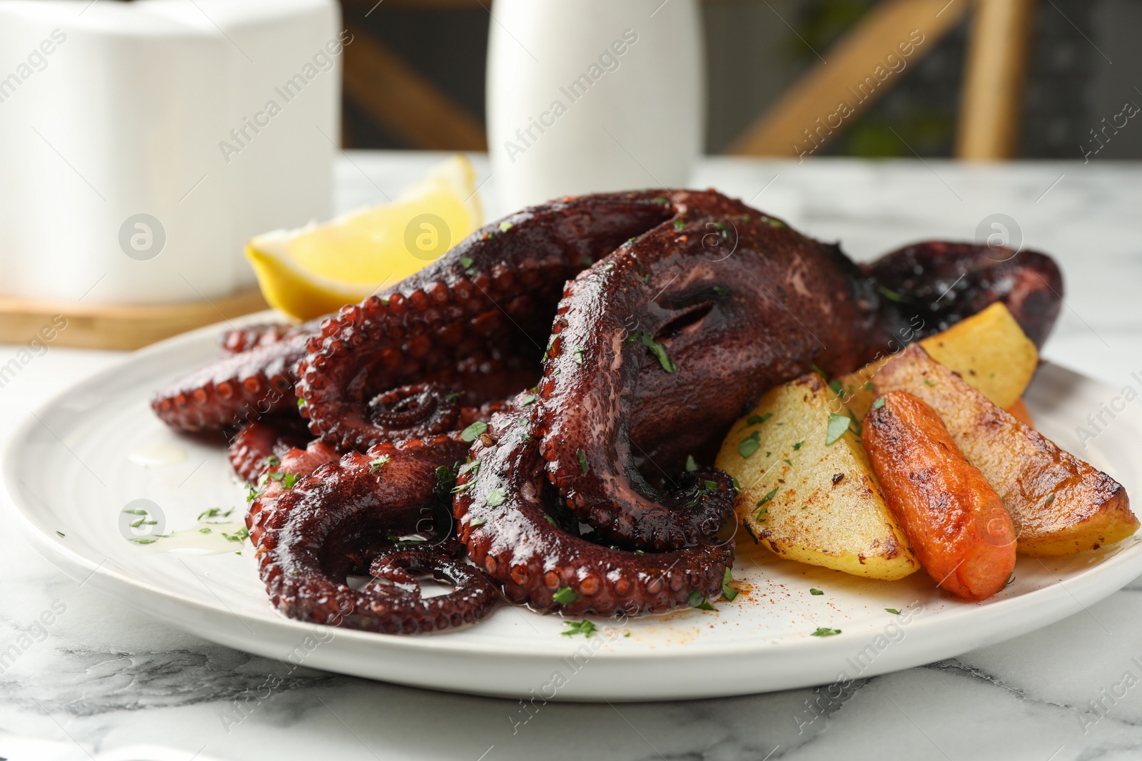 Photo of Roasted octopus with vegetables on white marble table, closeup