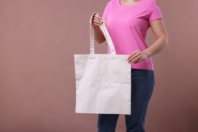 Photo of Woman with blank shopper bag on dark beige background, closeup. Mockup for design