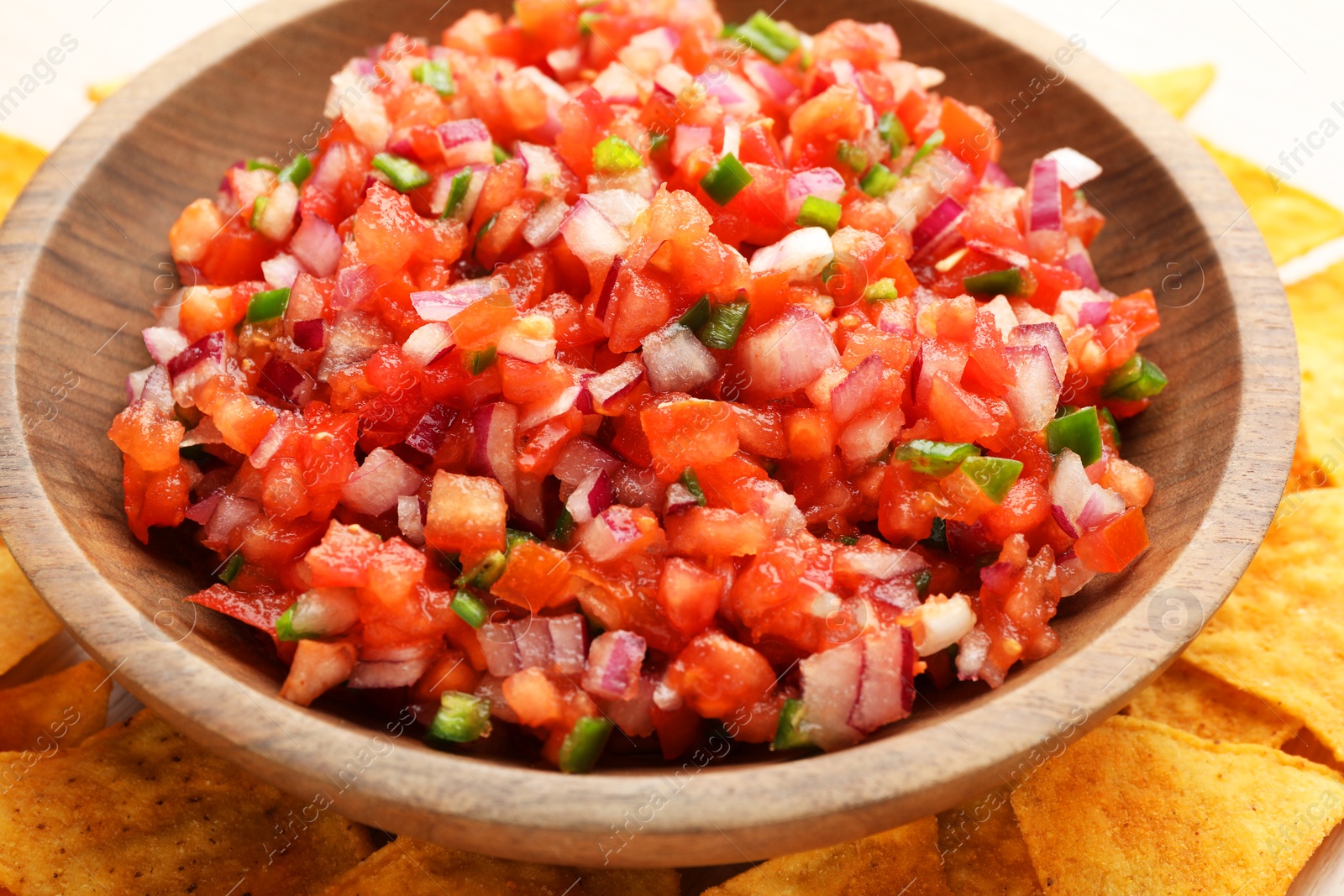 Photo of Delicious salsa in bowl and nacho chips on table, closeup