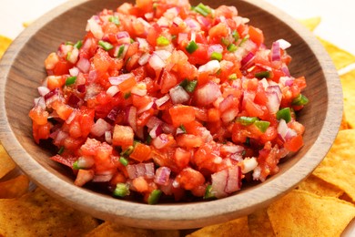 Photo of Delicious salsa in bowl and nacho chips on table, closeup