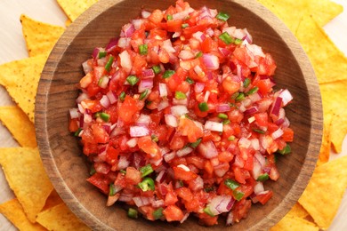 Photo of Delicious salsa in bowl and nacho chips on table, top view