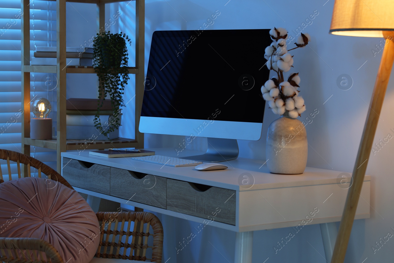 Comfortable workplace with computer on desk at home office in evening Photo of Comfortable workplace with computer on desk at home office in evening