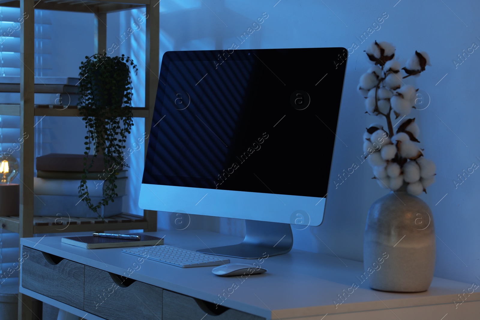 Comfortable workplace with computer on desk at home office in evening Photo of Comfortable workplace with computer on desk at home office in evening