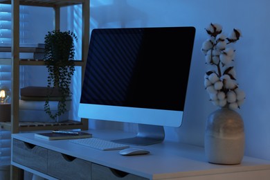 Photo of Comfortable workplace with computer on desk at home office in evening