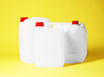 Photo of Three plastic canisters with caps on yellow background